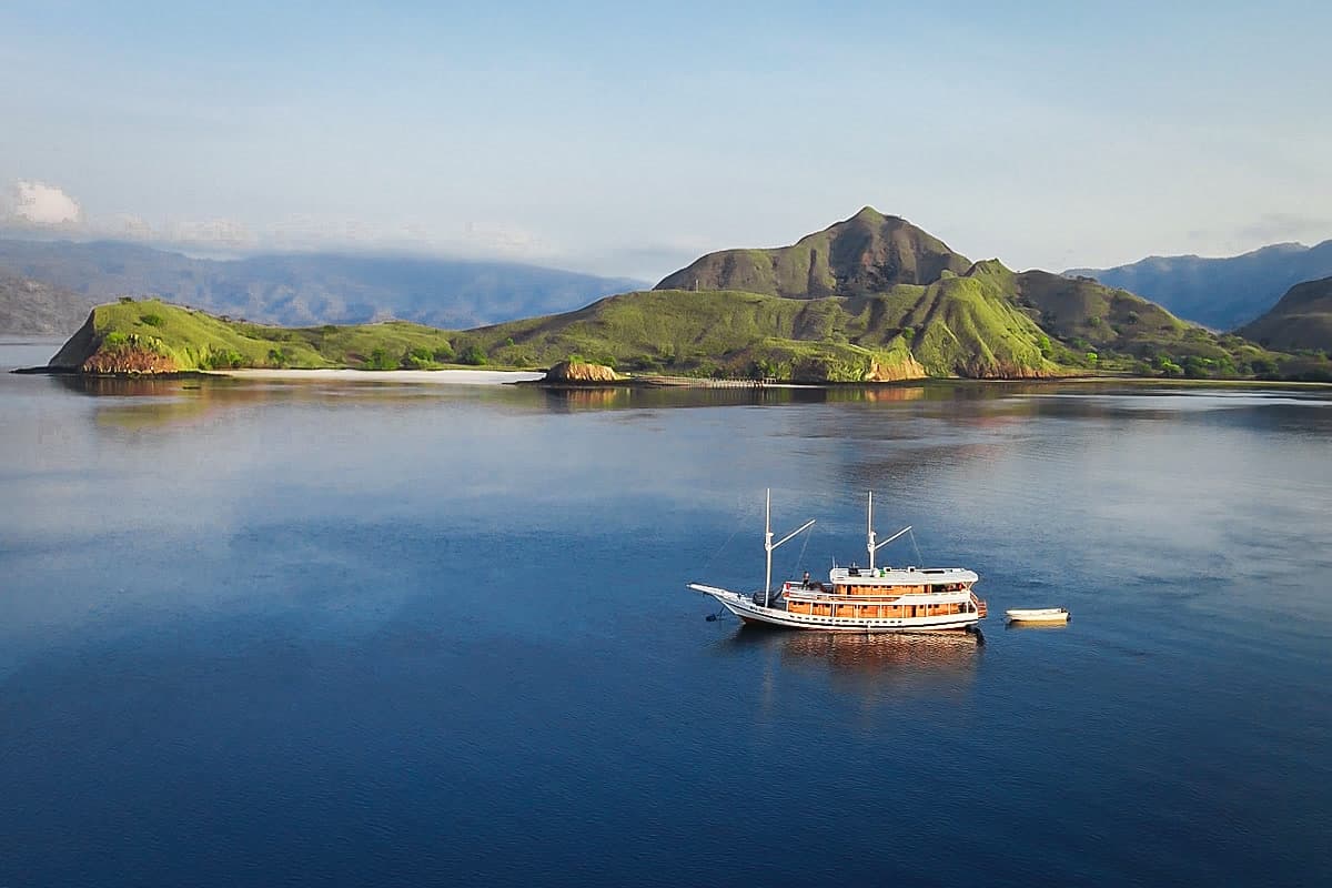 A private phinisi boat at anchor in a Komodo Islands bay