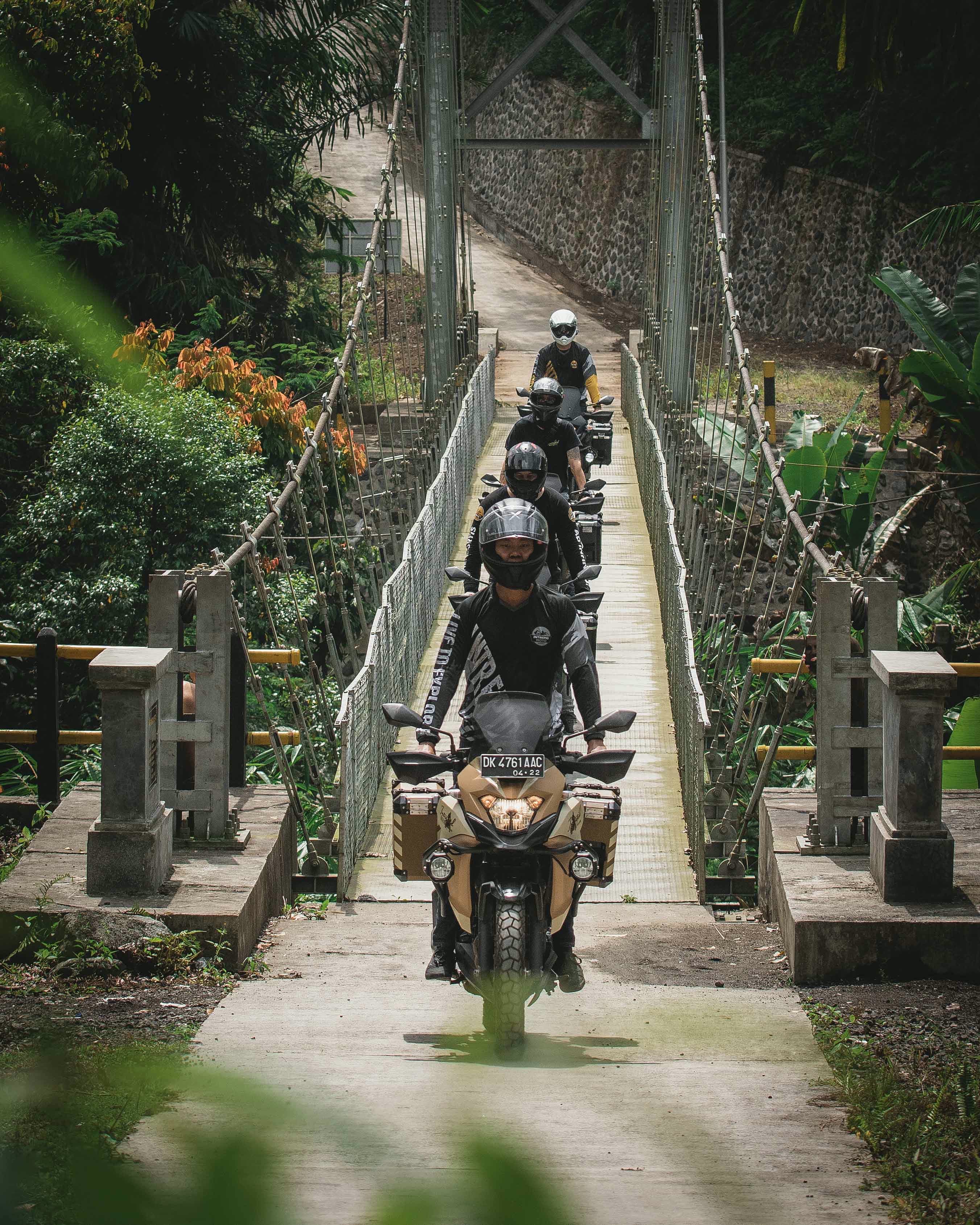 Intrepid Moto riders crossing a suspension bridge