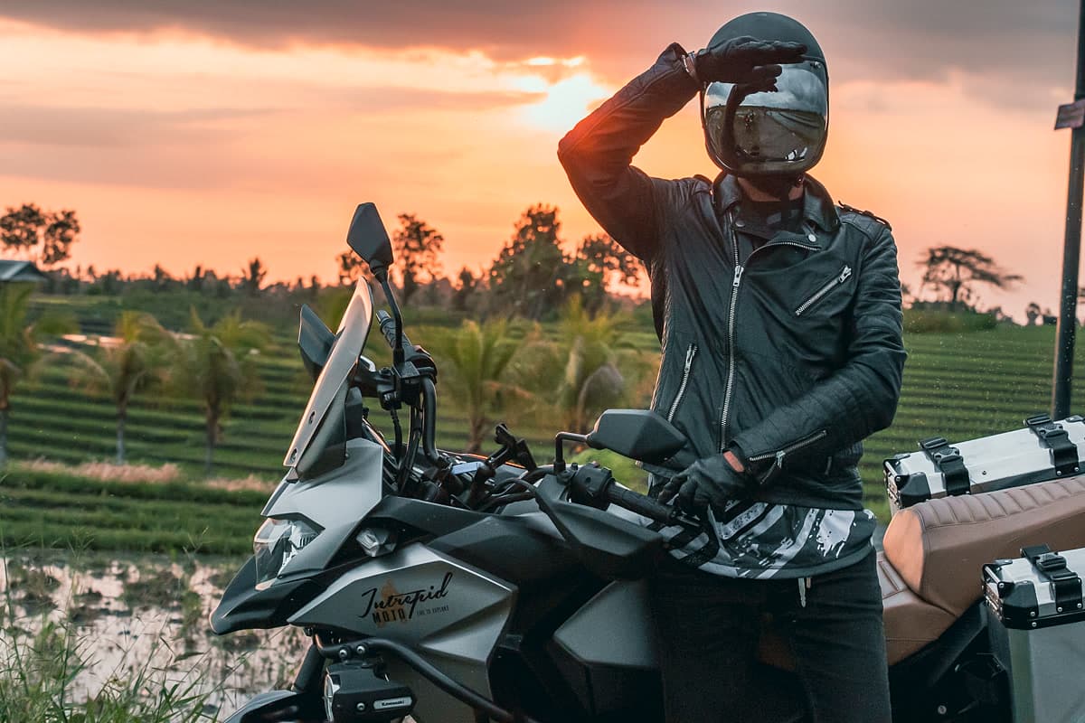 A motorcycle rider silhouetted against a Bali sunset