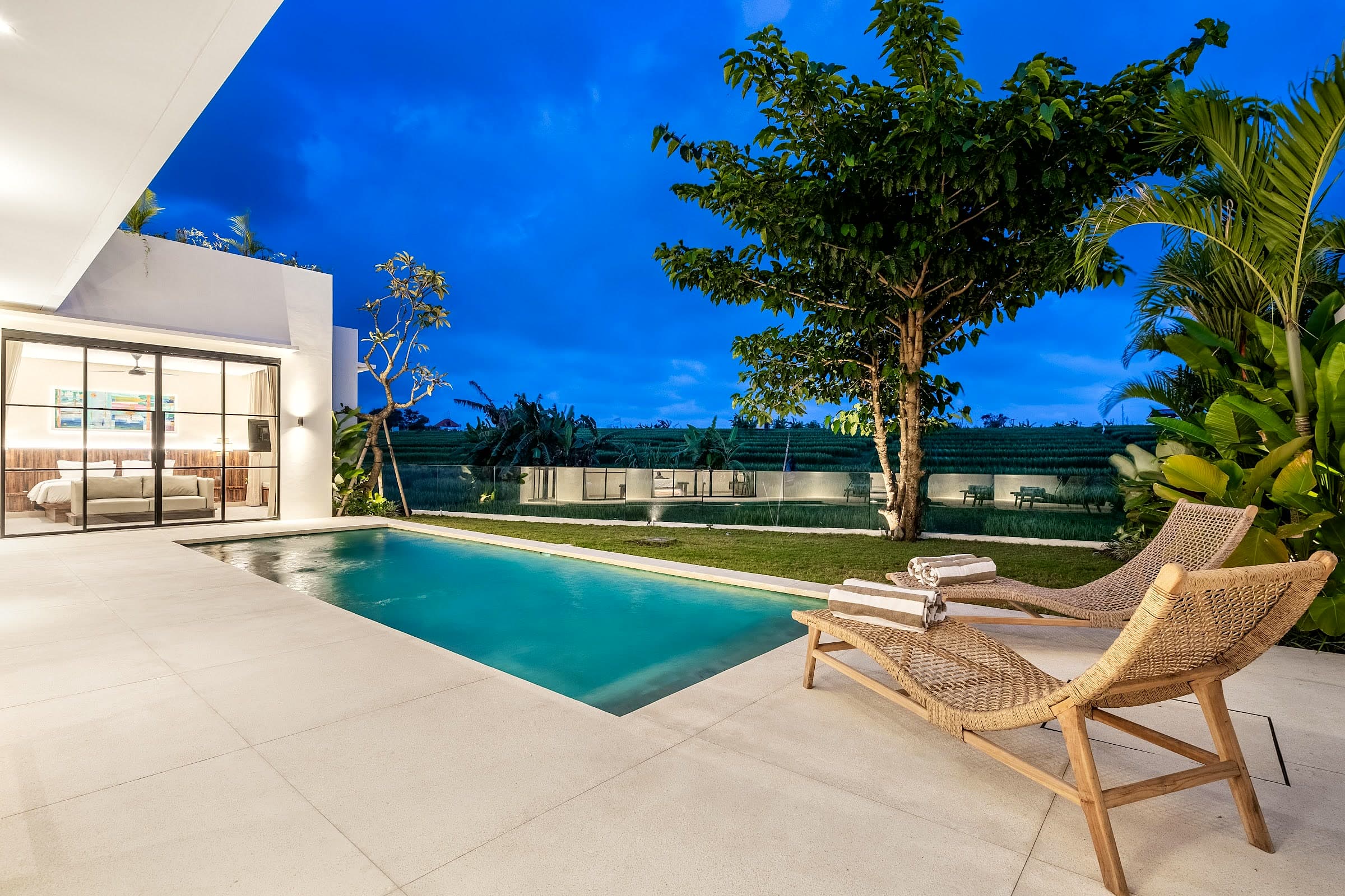 Villa Rice pool deck at twilight with the rice field beyond